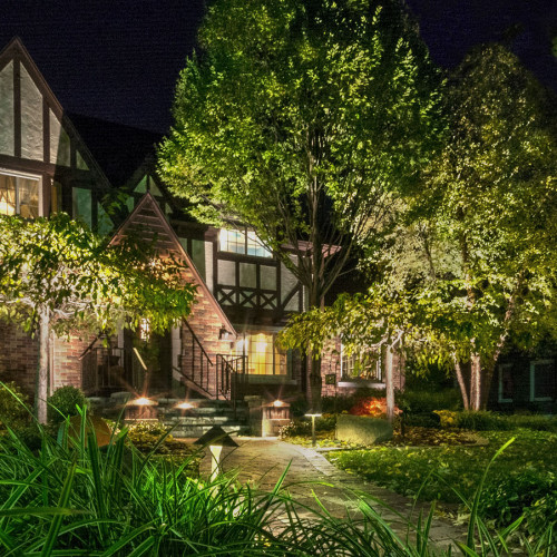 Landscape Lighting Image Tudor Style home lit by Encore brand LED brass fixtures by Bundschuh Landscape Center located in Genesee County, MI